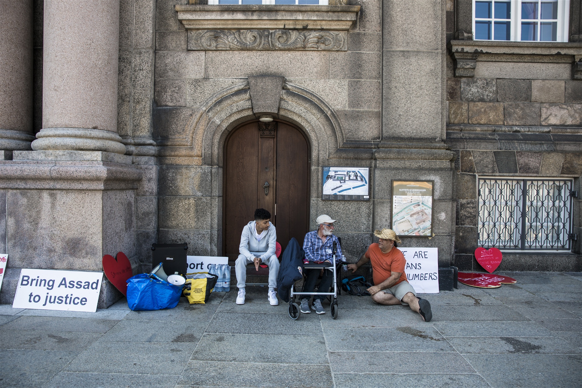 Mohammed Barakat, Abu Jakub och Samir Abdullah Barakat utanför Christiansborg, omgivna av skyltar.