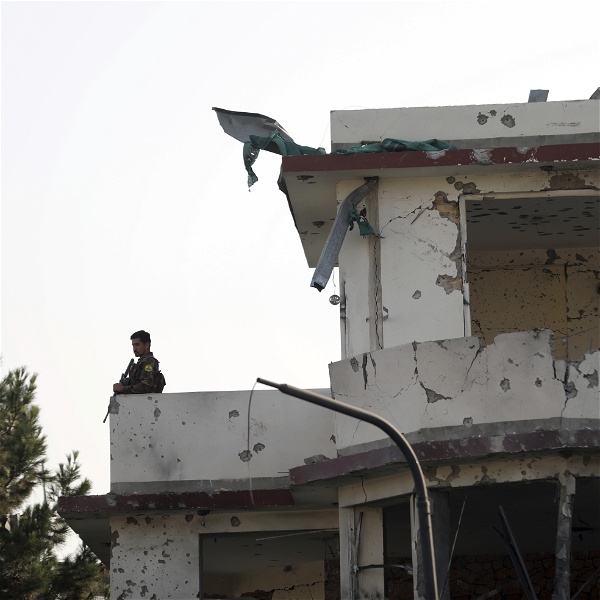 En soldat ståendes på en balkong på ett sönderskjutet hus.