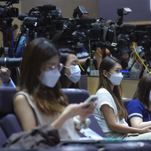 Journalister på en presskonferens framför en rad med kameror.