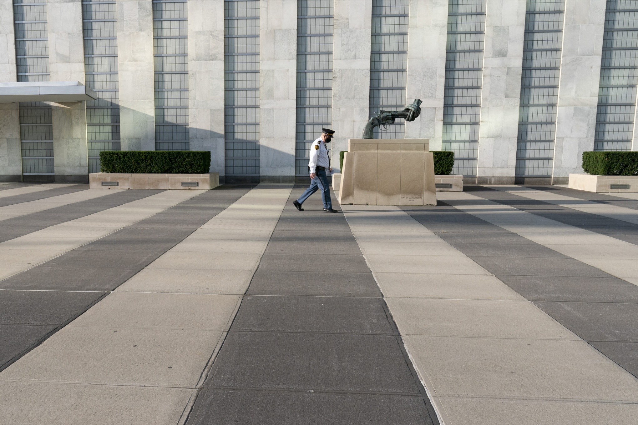 En man passerar utanför FN:s högkvarter. En skulptur av en pistol med pipan ihopknuten till en knut syns.