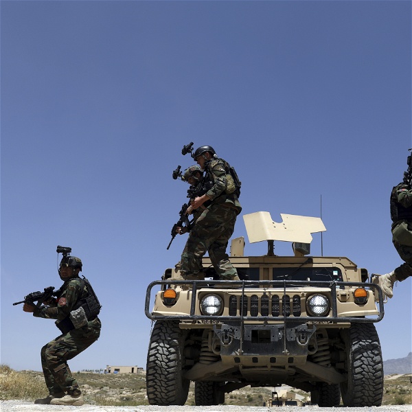 Afghanska soldater med maskingevär och kameror på hjälmarna hoppar ned från ett pansarfordon.
