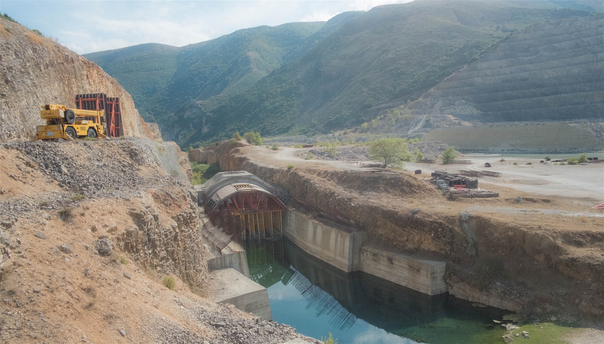 Dammen i Kalivac ligger nu nedlagd och Arbetaren jagas bort av vakter som ska förhindra stölder. För att ge plats åt dammbygget har halva sidan av en bergsvägg grävts bort, och förfallit. Det syns tydligt på de kvarvarande maskinerna och byggnaderna. Dammen är till 30 procent färdigbyggd. Foto: Enes Mehmedagic