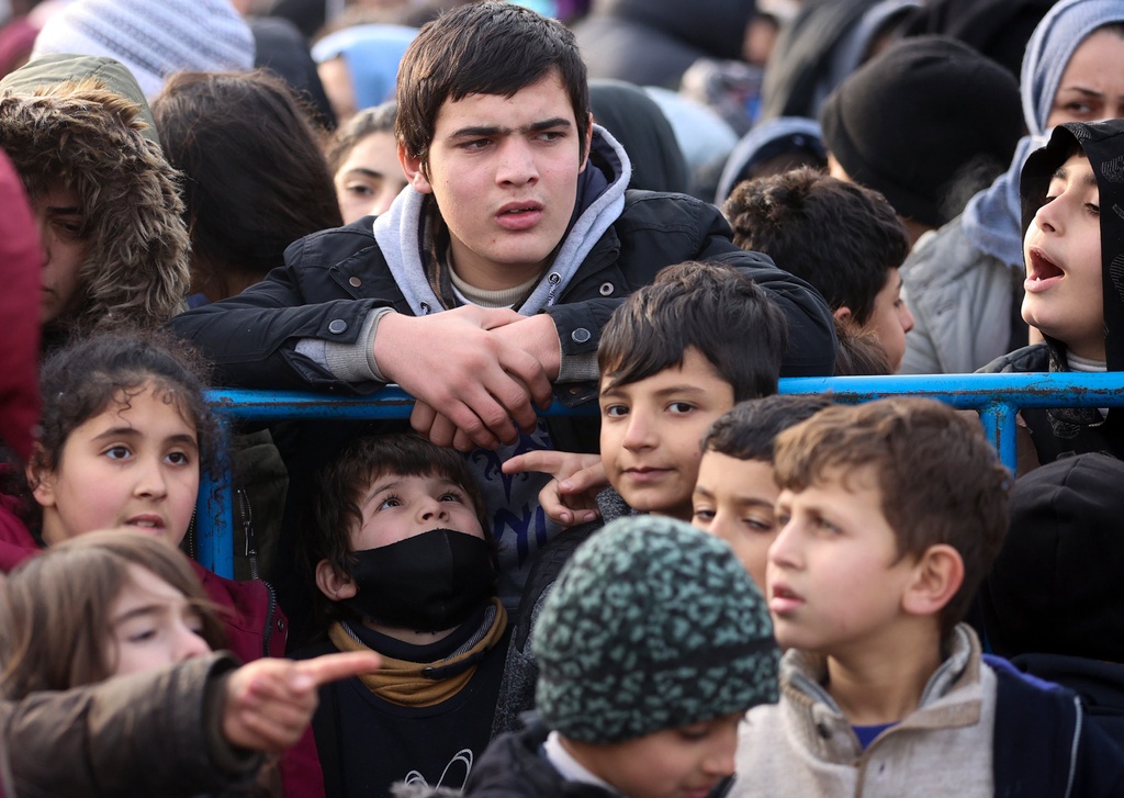 Migranter samlas för att få varma kläder intill ett logistikcenter vid checkpointen "Kuznitsa" vid gränsen. Foto:  Leonid Shcheglov/AP/TT
