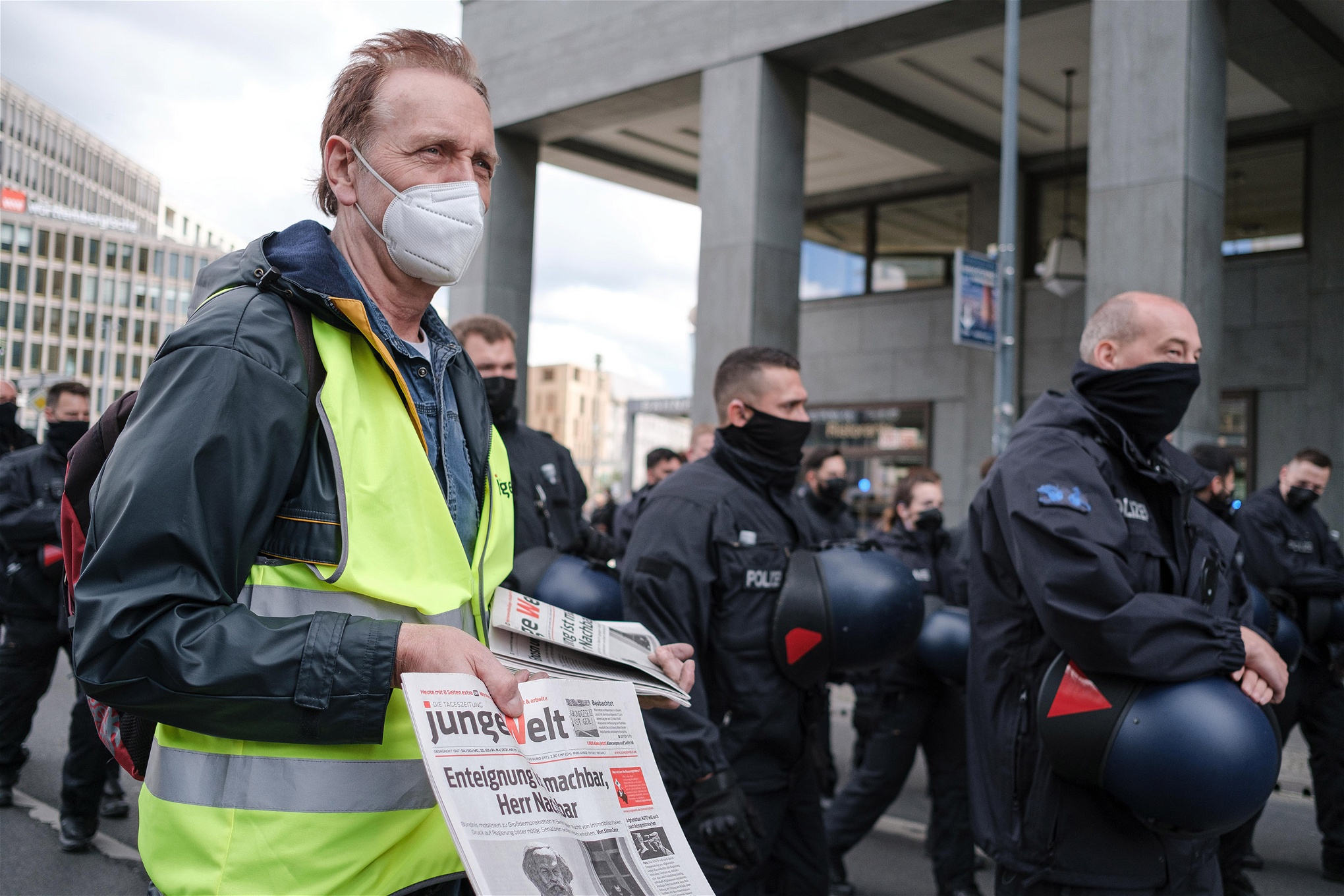 Tidningsförsäljare med reflexväst och munskydd under en demonstration.