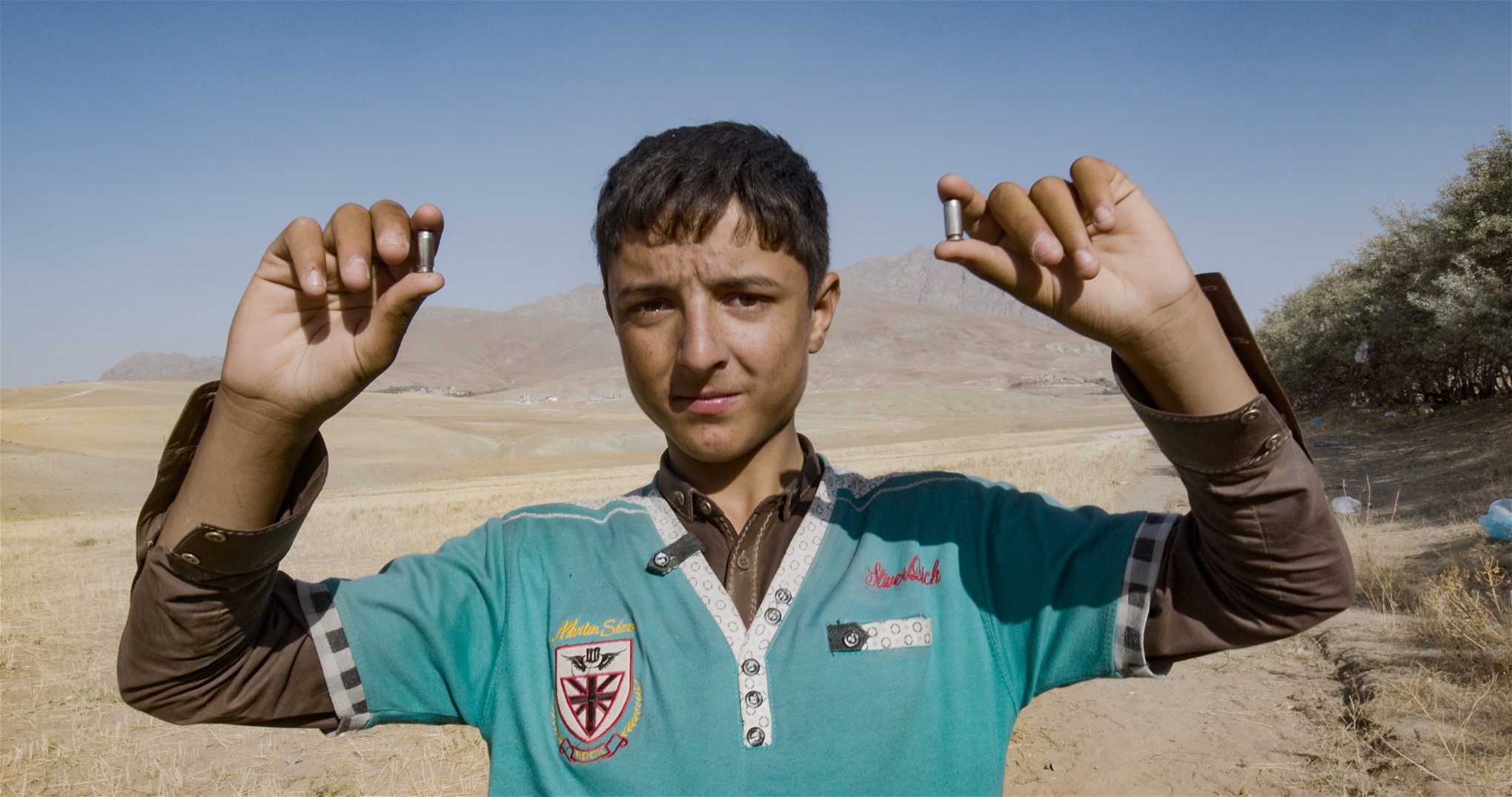 En 13-årig afghansk pojke visar upp patronhylsor från polisens stormning. Foto: Sebastian Peña