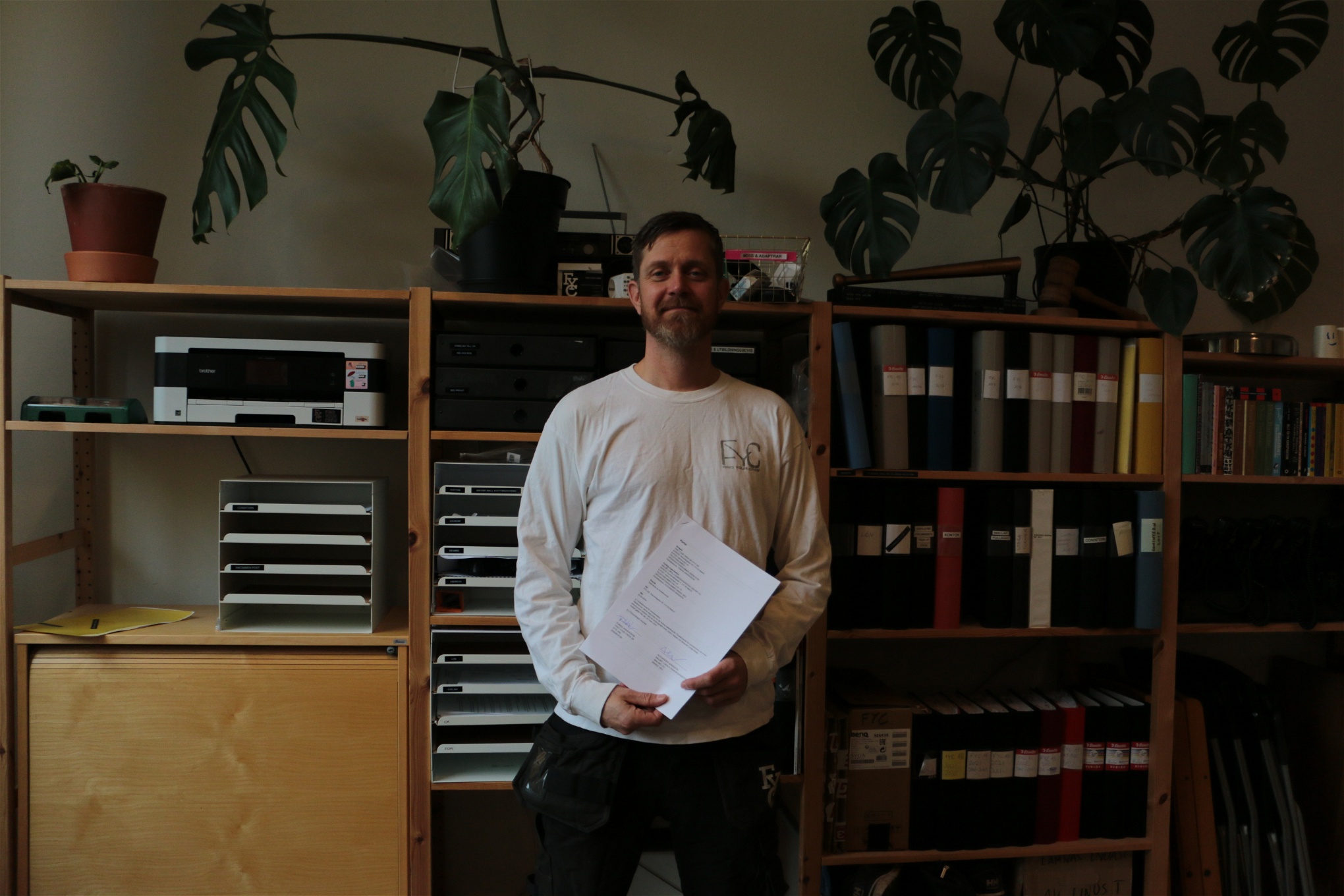 Tobias Andersson står med ett kollektivavtal i handen framför en bokhylla