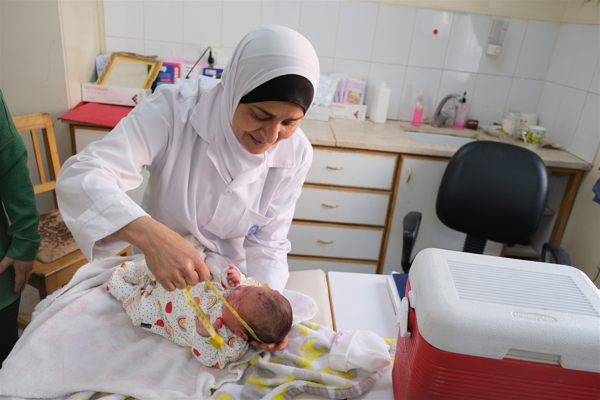 Sjuksköterskan Najwa mäter ett spädbarns huvud med ett måttband.