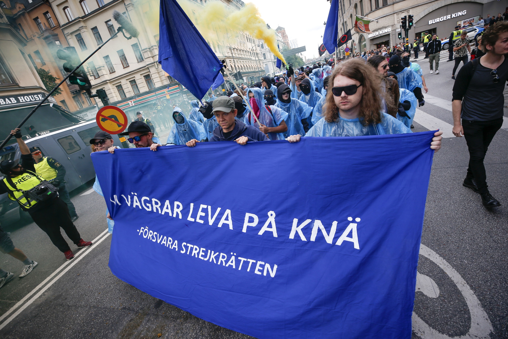 demonstranter med en stor blå banner där det står försvara strejkrätten